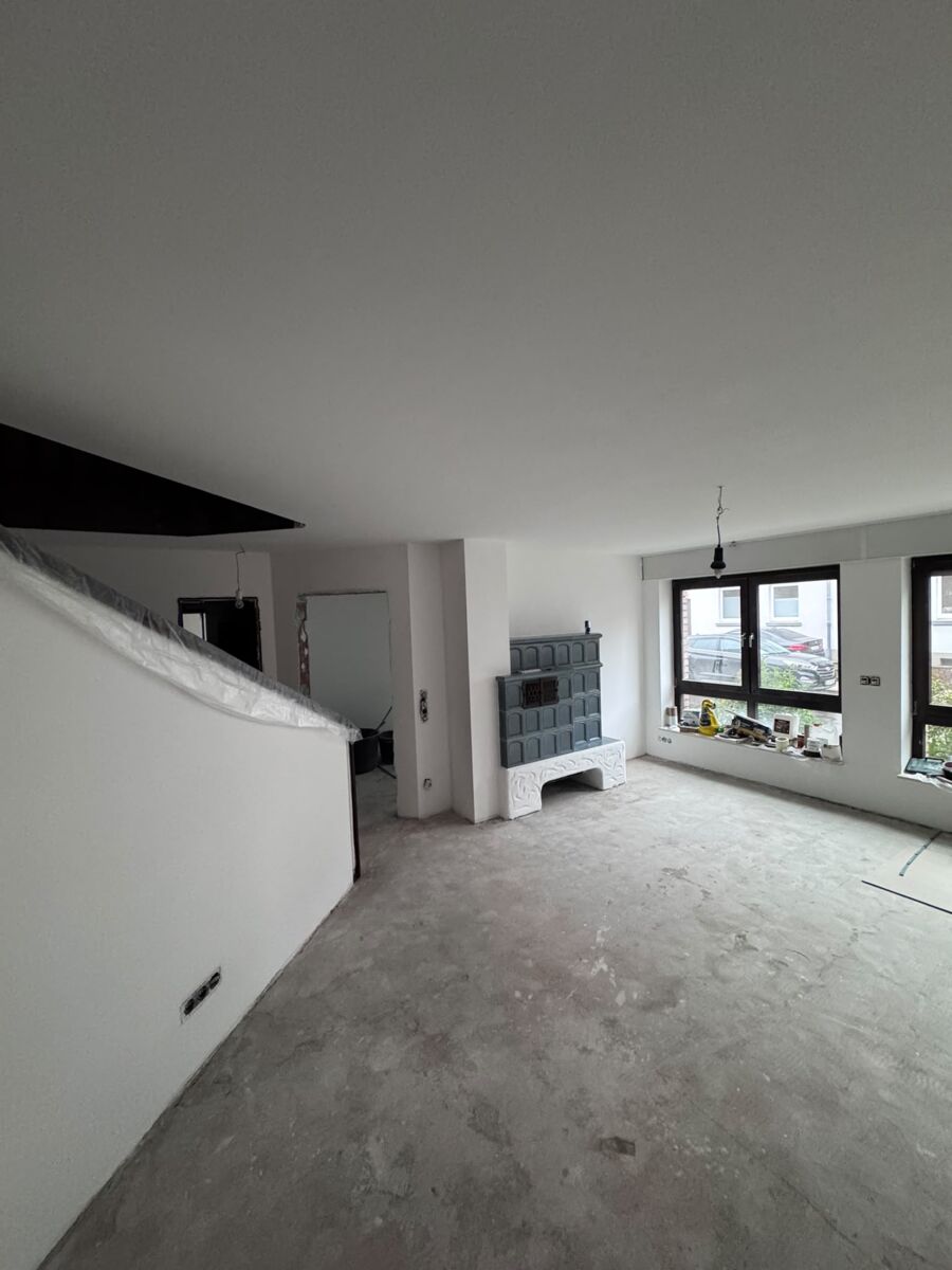 Sanierter heller Wohnraum mit Kamin, großen Fenstern und neuem Estrich